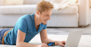 young man shopping online with a credit card ready to make a purchase