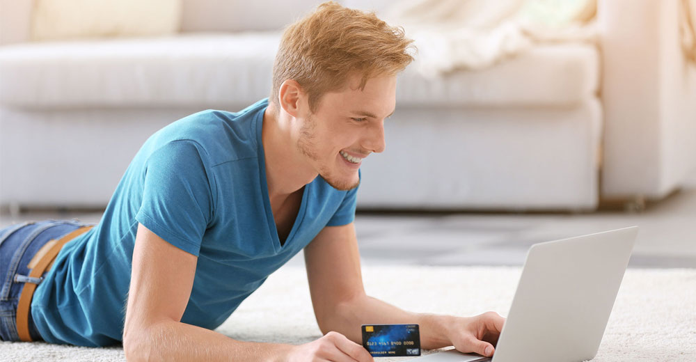 young man shopping online with a credit card ready to make a purchase