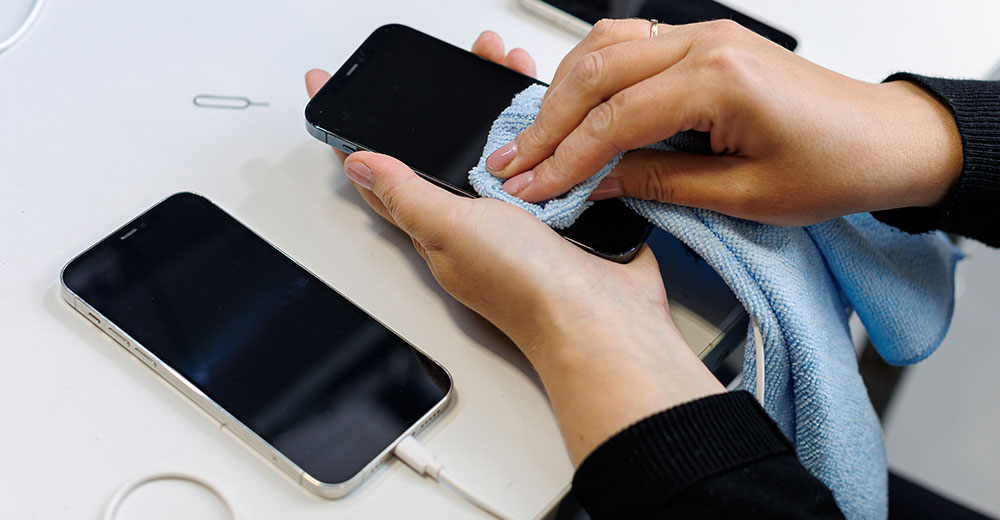 Cleaning used smartphones to prepare them for resale.