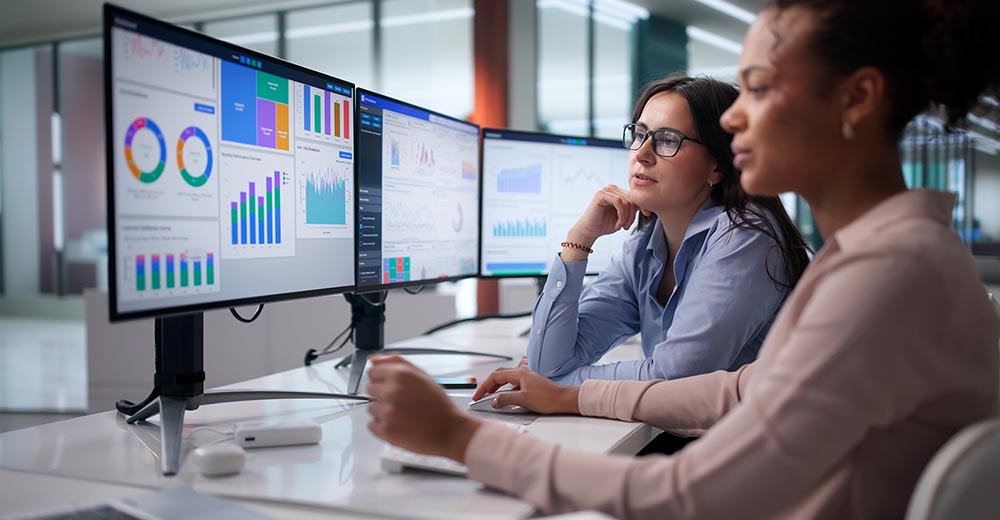 Sales team reviewing performance data and analytics dashboards on multiple monitors